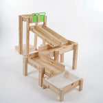 Wooden play structure with multiple levels and green toy bins on a white background